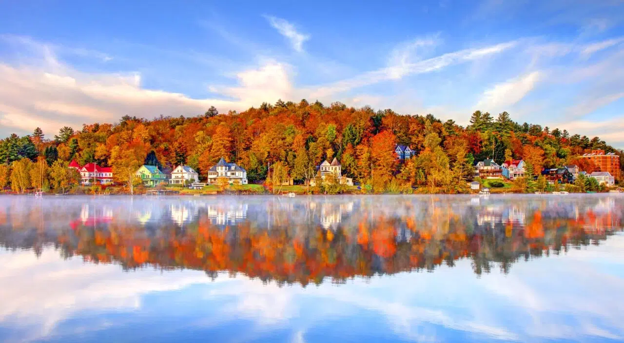 Saranac Lake surrounded by autumn leaves reflected in water
