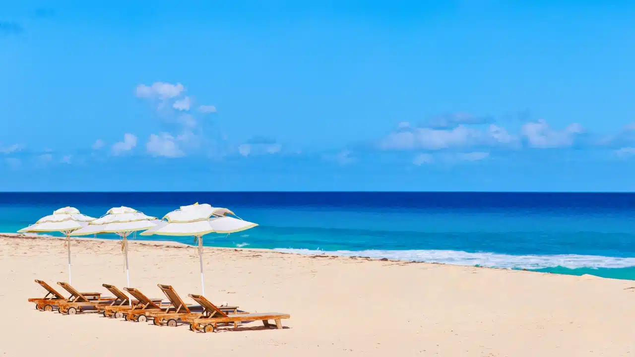 Beach near The Valley, Anguilla with sun loungers, white umbrellas, and calm turquoise Caribbean waters