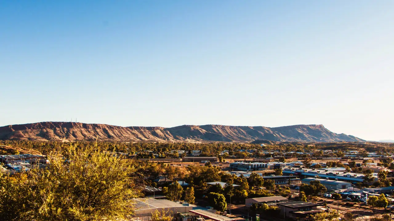 Panoramic view of Alice Springs, Northern Territory, Australia, showcasing the MacDonnell Ranges, expansive outback scenery, and the town's unique desert landscape, making it a top destination for exploring the Australian Outback.